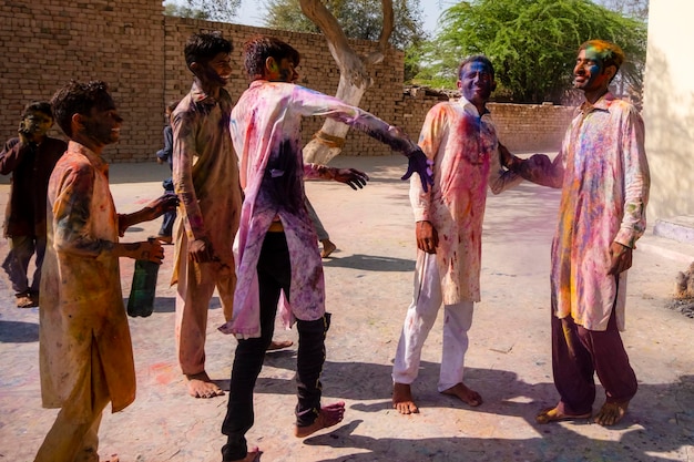 Foto een groep mensen viert holi, waarvan er één gekleurd is.