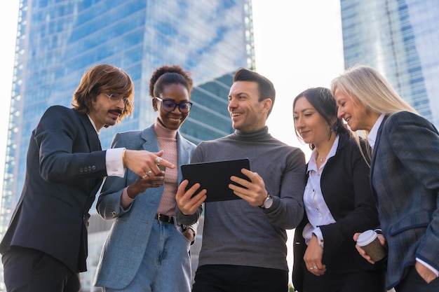 Een groep multi-etnische zakenmensen in een bedrijvenpark die lachend naar een tablet kijken