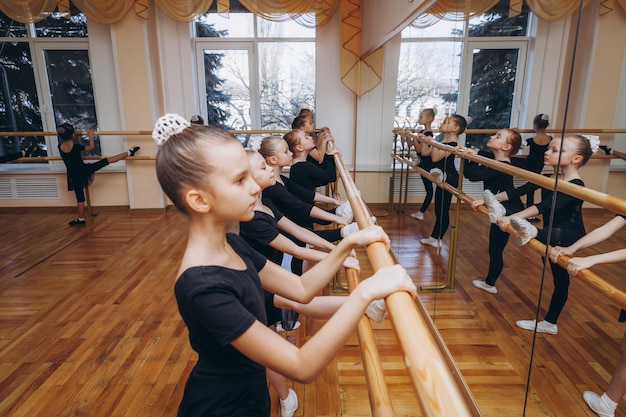 Een groep tienermeisjes in sportkleding die beenrekoefeningen doen in de buurt van de barre. ritmische gymnastiek.