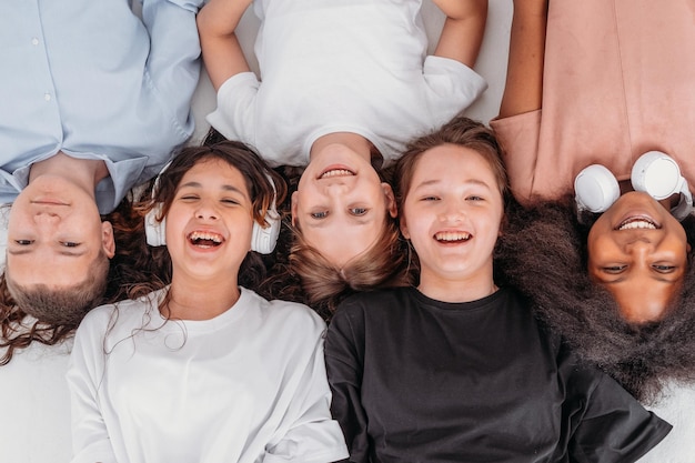 Een groep tieners ligt op de grond en kijkt naar de camera en lacht. uitzicht van bovenaf