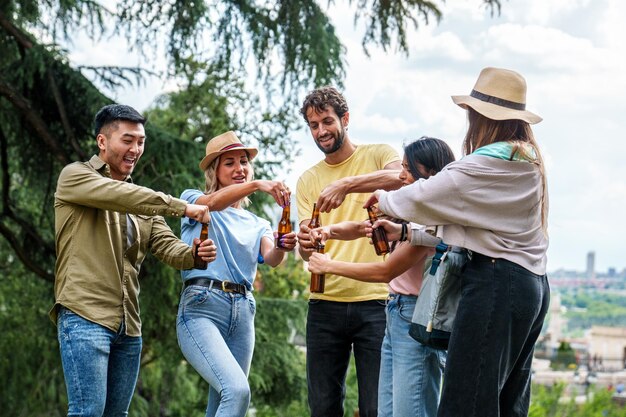 Een groep uiteenlopende vrienden die met bierflessen in een park een bewolkte dag buiten genieten