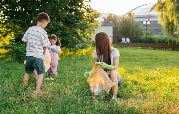 Een groep volwassenen en kinderen samen bij zonsondergang houdt zich bezig met afvalinzameling in het park Milieuzorg afvalrecycling Afval sorteren