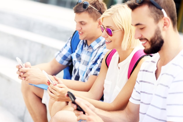 een groep vrienden die smartphones gebruiken op de campus