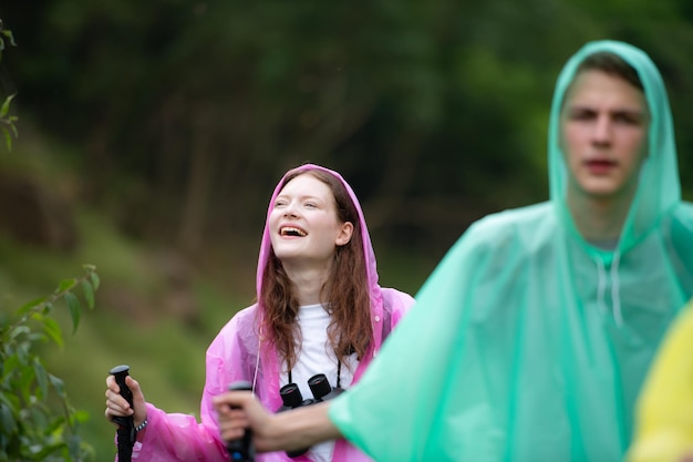 Een groep vrienden in regenjassen die op het bospad wandelen