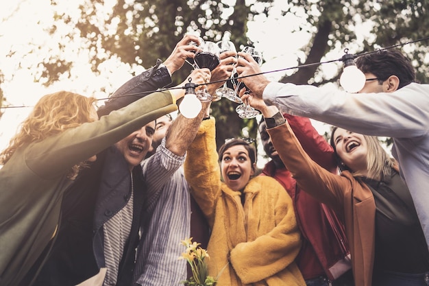 Een groep vrienden van verschillende etnische achtergronden ontmoeten elkaar bij zonsondergang op het platteland om samen te proosten op het terras van het boerderijrestaurant, mensen die lifestyle concept vintage filter drinken