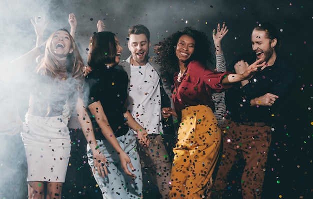 Foto een groep vrolijke jonge vrienden die dansen en confetti gooien terwijl ze genieten van een feestje in een nachtclub