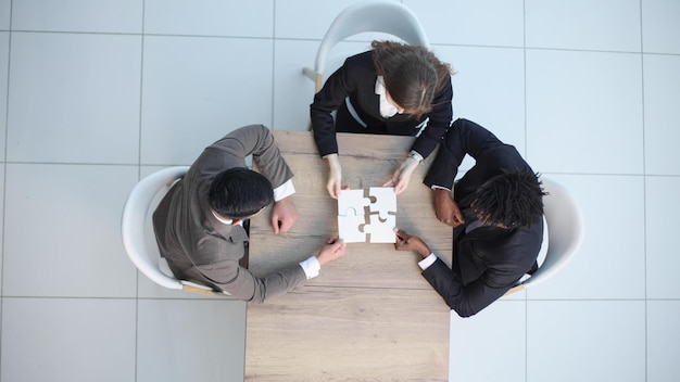 Een groep zakenlieden zit aan tafel en maakt een puzzel.