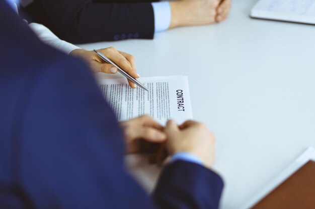 Een groep zakenmensen, mannen en een vrouw, bespreken de details van een contract tijdens een vergadering in een modern kantoor. Bespreking tijdens onderhandelingen of op de werkplek. Teamwerk, partnerschap en bedrijfsconcept