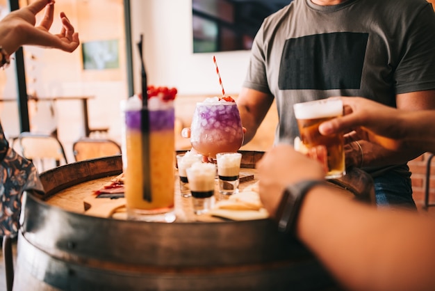 Een groepje vrienden zit 's zomers op het terras achter een houten vat met cocktails en een hapje