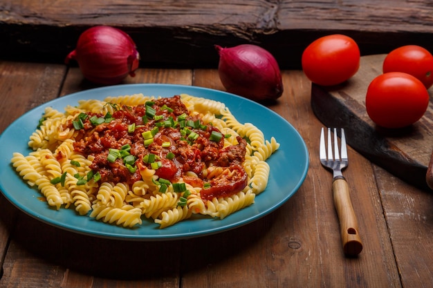 Foto een groot bord bolognese pasta in tomaat met groene uien op een houten tafel