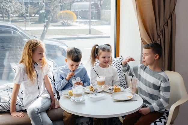 Een groot gezellig gezelschap van kinderen viert de vakantie in een café met een heerlijk toetje. De dag van de geboorte.
