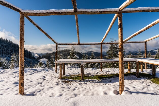 Een groot, onbedekt prieel op de top van de berg staat op een besneeuwde witte weide badend in het licht van de felle koude zon in de Karpaten