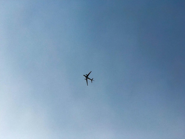 Een groot passagiersvliegtuig met vleugels vliegt hoog in de blauwe lucht