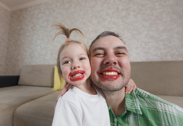 Een groot portret van een vader en dochter met felgekleurde lippen