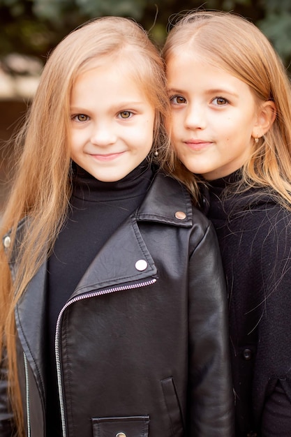 een groot portret van twee blonde meisjes vriendinnen met lang haar in zwarte sweatshirts