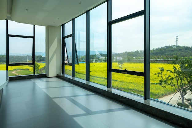 Een groot raam in een groot kantoorgebouw met op de achtergrond een groen veld.