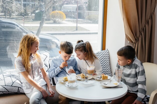 Een groot vriendelijk gezelschap van kinderen viert de vakantie in een café met een heerlijk toetje. de dag van de geboorte.