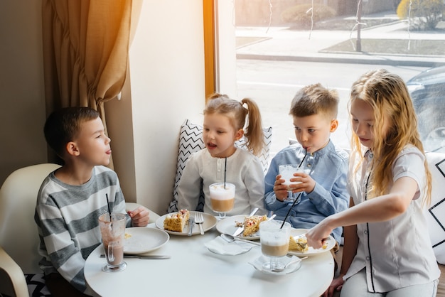 Een groot vriendelijk gezelschap van kinderen viert de vakantie in een café met een heerlijk toetje. De dag van de geboorte.