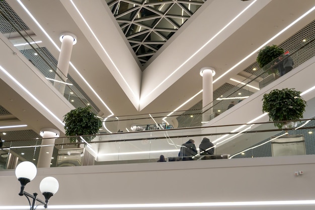 Een groot winkelcentrum met meerdere verdiepingen met roltrappen en liften Uitzicht op het interieur van de luchthaven met sierplanten en grote lampen