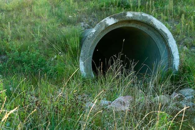 Een grote betonnen buis om de rivier onder de snelweg door te leiden Lekkend vuil water uit grote betonnen buizen Vuil rioolwater uit de buis milieuvervuiling Milieuprobleem