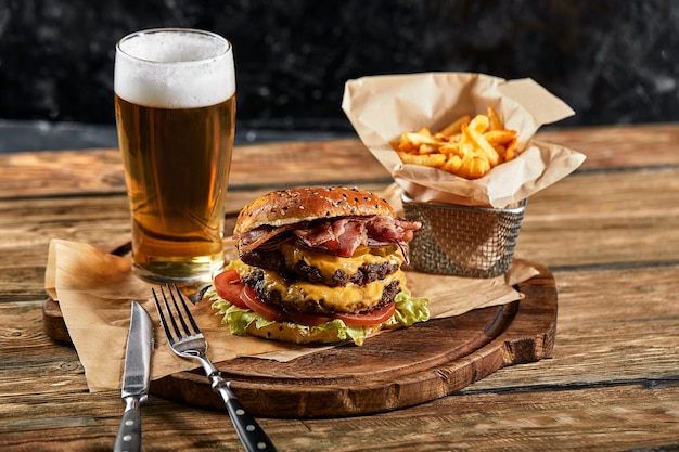 Een grote burger om van te watertanden met gegrilde runderpasteitje en verse groenten. Lekkere Amerikaanse cheeseburger op een houten bord. Klassieke zelfgemaakte burger in ambachtelijk papier.