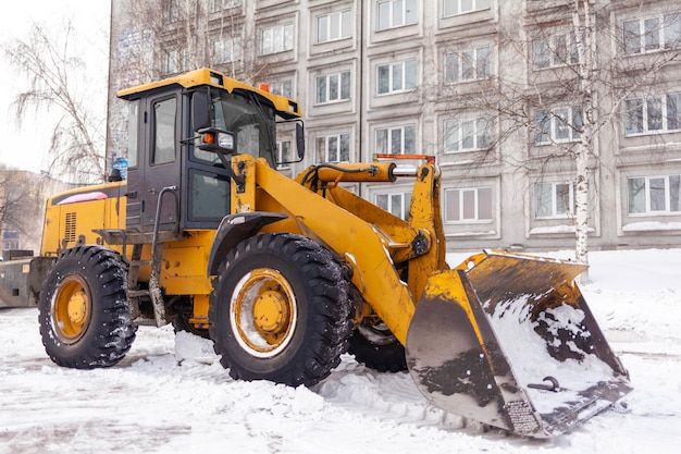 Een grote gele tractor verwijdert sneeuw van de wegReiniging van wegen in de stad van sneeuw in de winter
