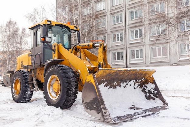 Een grote gele tractor verwijdert sneeuw van de wegReiniging van wegen in de stad van sneeuw in de winter