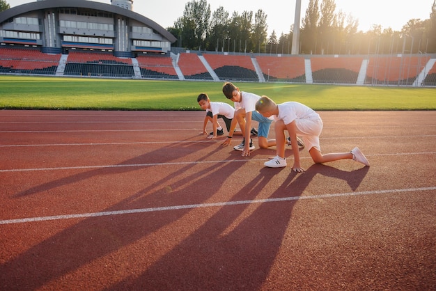 Een grote groep jongenskinderen krijgt bij de start les van een coach voordat ze tijdens zonsondergang naar het stadion rennen. Een gezonde levensstijl