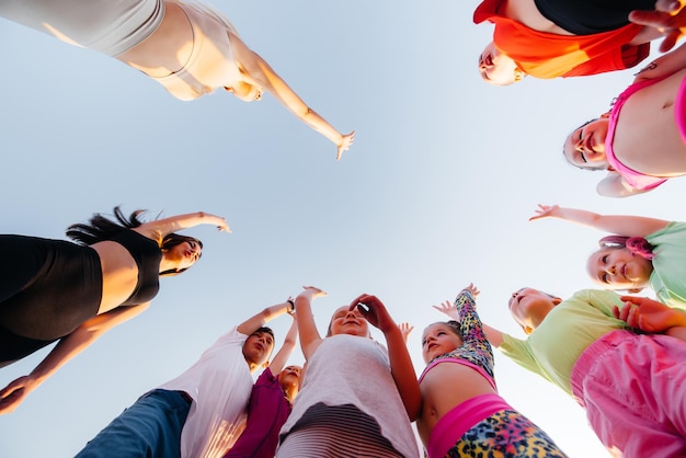 Een grote groep kinderen jongens en meisjes staan samen in een cirkel en vouwen hun handen afstemmen en verhogen de teamgeest voor de wedstrijd in het stadion tijdens zonsondergang een gezonde levensstijl