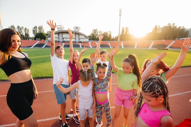 Een grote groep kinderen jongens en meisjes staan samen in een cirkel en vouwen hun handen afstemmen en verhogen de teamgeest voor de wedstrijd in het stadion tijdens zonsondergang Een gezonde levensstijl