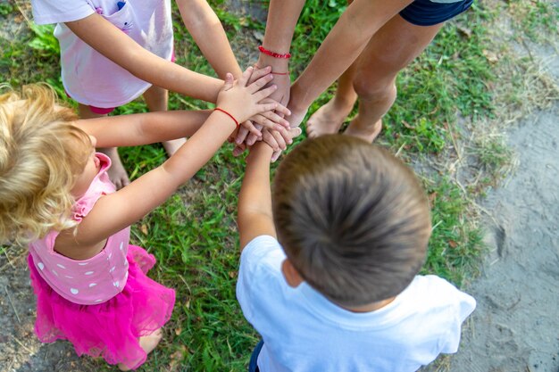 Foto een grote groep kinderen jongens en meisjes staan samen in een cirkel en zetten hun handen samen zich opzetten en verhogen teamgeest voor het spel