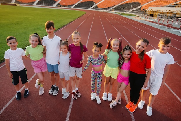 Een grote groep kinderen, jongens en meisjes, verheugt zich samen en zwaait met hun handen naar het stadion tijdens de zonsondergang na het spel Een gezonde levensstijl