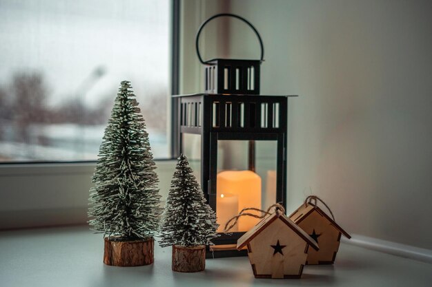 een grote kroonluchter met kaarsen, kerstbomen en houten huizen op de vensterbank in de winter e