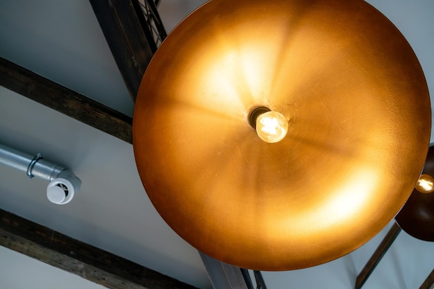 Een grote metalen kroonluchter hangt aan het plafond in het restaurant Interieurontwerp in een café Uitzicht op het plafond in het kantoor Designerplafonds decoratieve houten balken Ventilatiepijp