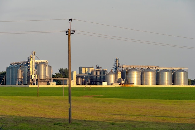 Een grote moderne fabriek voor de opslag en verwerking van graangewassen uitzicht op de graanschuur op een zonnige dag tegen de blauwe lucht Einde oogstseizoen zilveren silo's op agro-fabriek