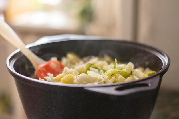 Een grote pilaf pannenkom met een mix van groenten, koken in de keuken