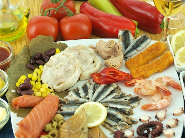 Een grote schaal met zeevruchten, waaronder vis, vis, maïs en tomaten.