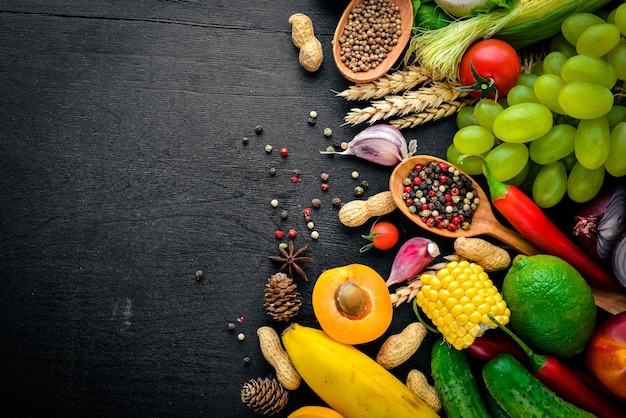 Een grote selectie van rauwe groenten, fruit en kruiden op een zwarte houten ondergrond Vrije ruimte voor uw tekst Bovenaanzicht