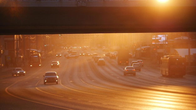 Een grote stadsauto die op de weg onder de brugzonsondergang rijdt