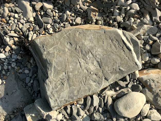 Een grote steen ligt op een zeekiezel op het strand. stuk rots. Hoge kwaliteit foto