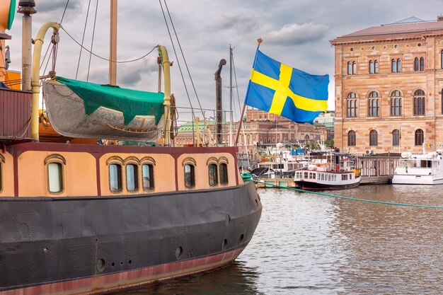 Foto een grote zweedse vlag zwaait op een boot in een drukke haven van stockholm, zweden.