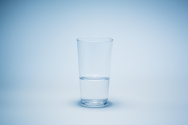 Een half glas water met blauwe achtergrond