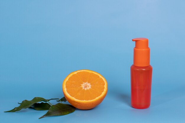 Een halve sinaasappel met folders en een cosmetische fles met een lotion, crème, body en haarlak. Citrus Natuurlijk Hygiëneconcept.