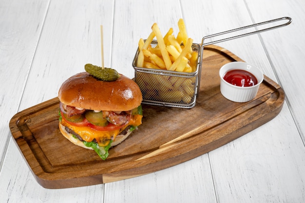Een hamburger en een mandje van frietjes met ketchup op houten bureau