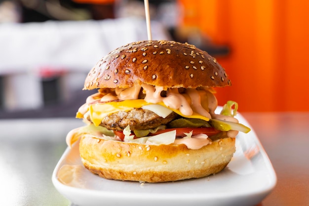 een hamburger met kaas en vlees erop ligt op een bord.