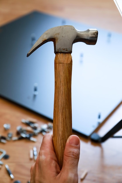 een hamer pakken om een grijs bureau in elkaar te zetten.