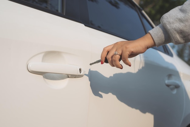 Een hand die een autodeur opent met een sleutel