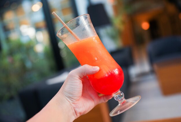 Een hand die een cocktail vasthoudt met een rietje erin