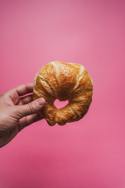 Een hand die een croissant vasthoudt