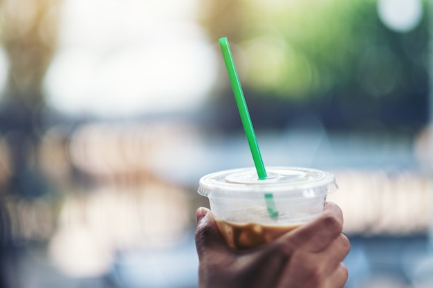 Een hand die een plastic glas ijskoffie met rietje vasthoudt